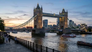 Iconic Tower Bridge over the River Thames with London skyline buildings at sunset.
