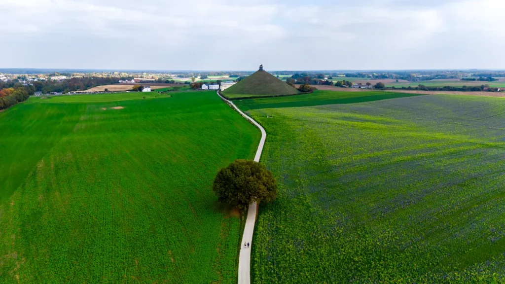 Aerial view of the historic Waterloo battlefield monument in lush green fields of Belgium.