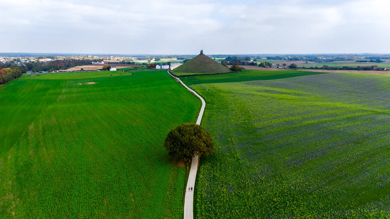 Aerial view of the historic Waterloo battlefield monument in lush green fields of Belgium.