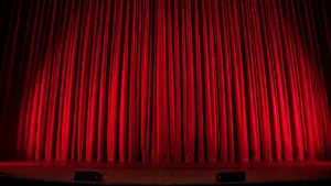Classic red velvet theater curtains closed on a stage at a performance venue.