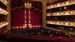 Grand interior of a historic opera house with tiered balconies and red velvet seats.