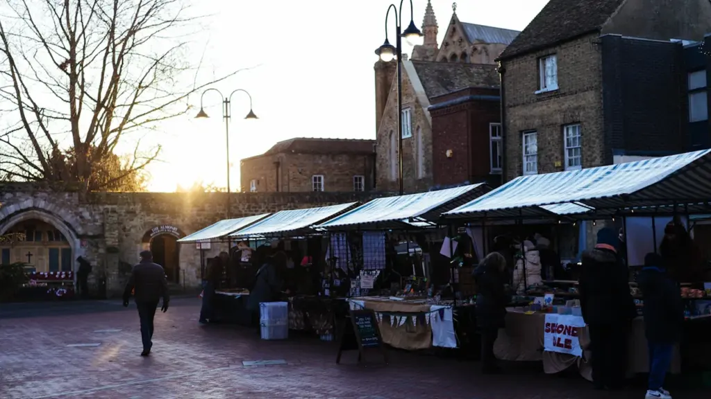 Outdoor market stalls in a historic British town setting at golden hour.