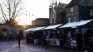 Outdoor market stalls in a historic British town setting at golden hour.