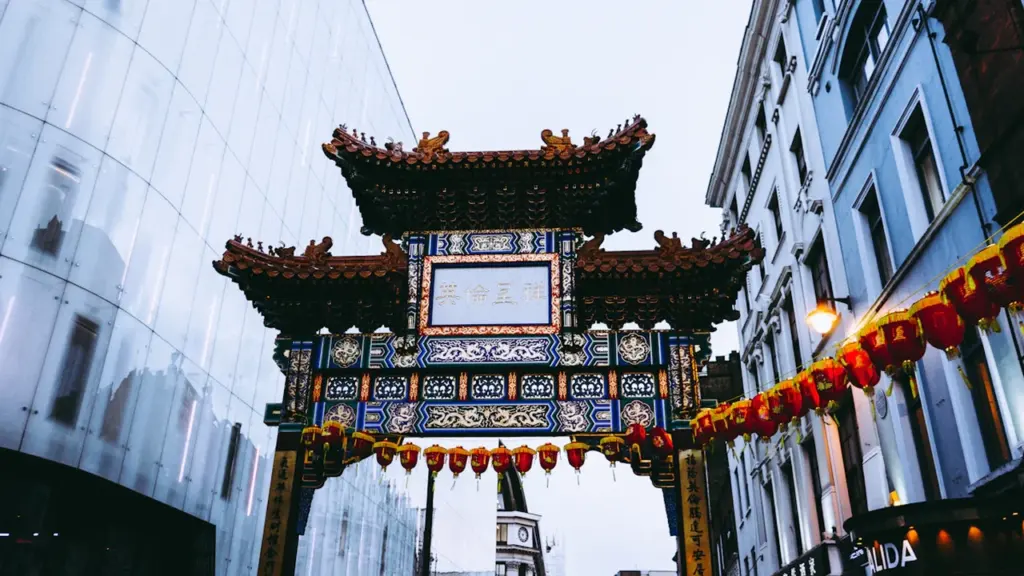 An ornate traditional archway situated in a bustling urban street environment.
