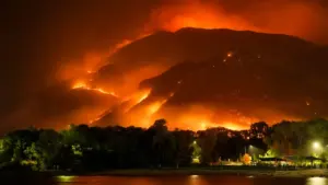 Large wildfire burning intensely on a mountain ridge at night near Nethy Bridge.