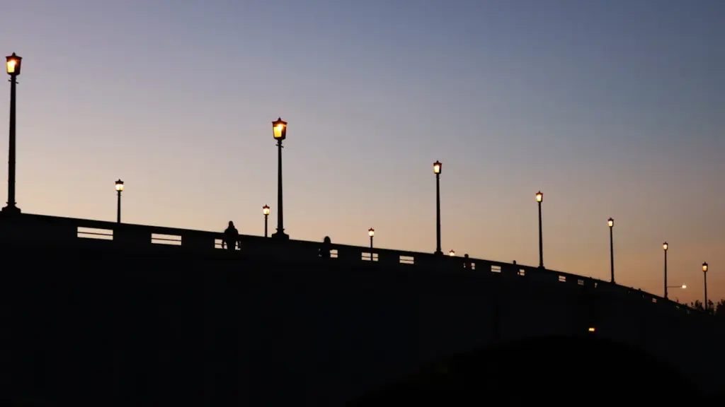 Silhouette of Wandsworth Bridge at sunset with city lighting in London.