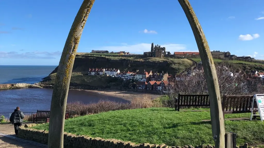 Large whale bone arch overlooking Whitby Abbey and the coastal town in England.