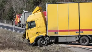 Yellow lorry involved in a road accident on a rural roadside verge.