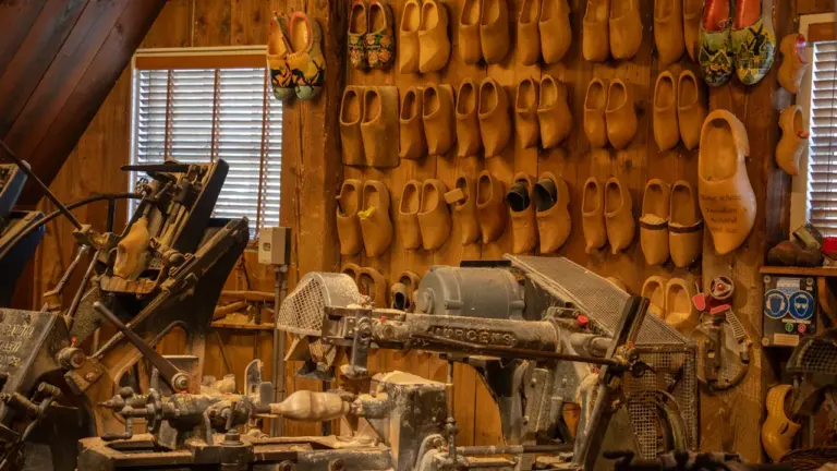 An industrial workshop featuring wooden machinery and rows of displayed traditional wooden clogs.