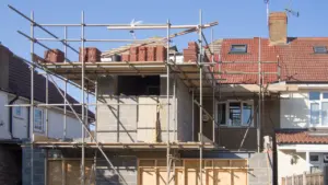 Residential building extension under construction featuring scaffolding on a typical London street.
