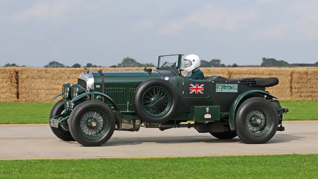 Vintage green car driving at Sywell Aerodrome during a UK heritage event.