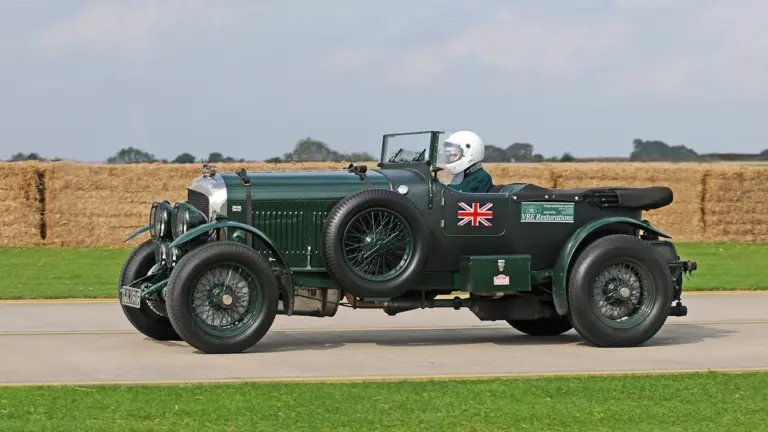 Vintage green car driving at Sywell Aerodrome during a UK heritage event.