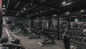Modern gym interior featuring rows of weight benches and various fitness equipment for training.