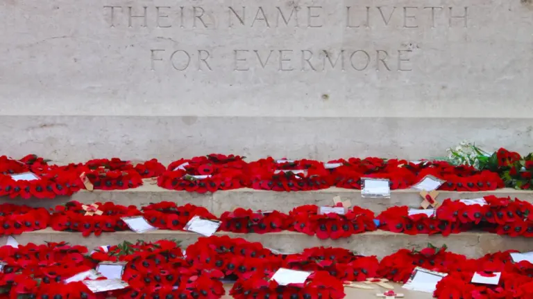 British World War One memorial with red poppy wreaths on stone steps.