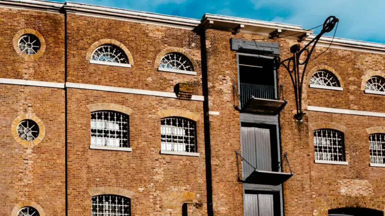 Classic red brick warehouse building with industrial hoist and arched windows in London.