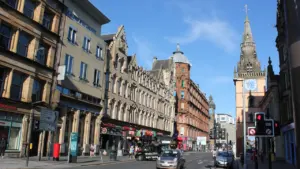 A busy Glasgow city street featuring tall historic buildings and urban traffic.