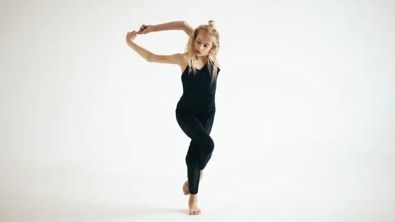 Young dancer performing a graceful and energetic contemporary move in black clothing.