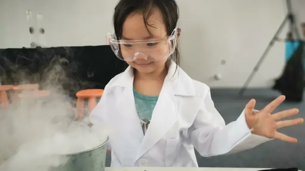 Young girl in lab coat and goggles participating in a science workshop.