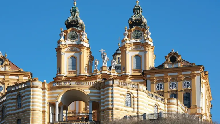 Majestic historic monastery building featuring two tall ornate towers against a clear blue sky.