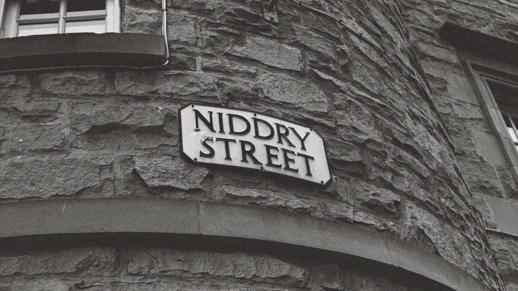 Close-up of a street name sign on a historic stone building facade.