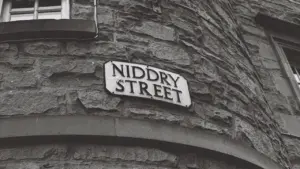 Close-up of a street name sign on a historic stone building facade.