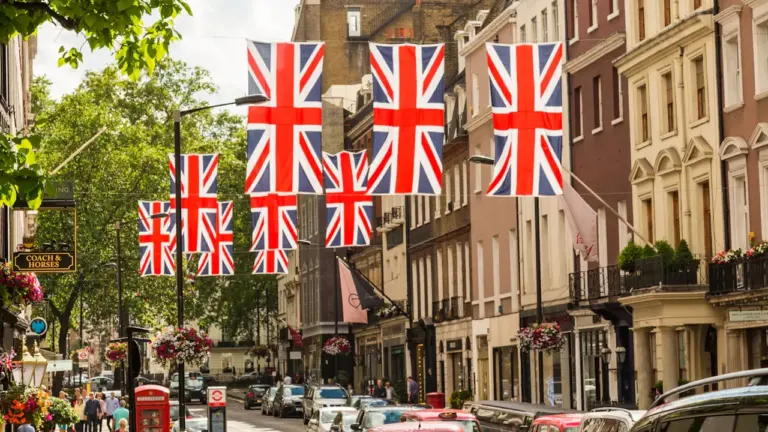 British flags hanging over a bustling city street with classic architecture