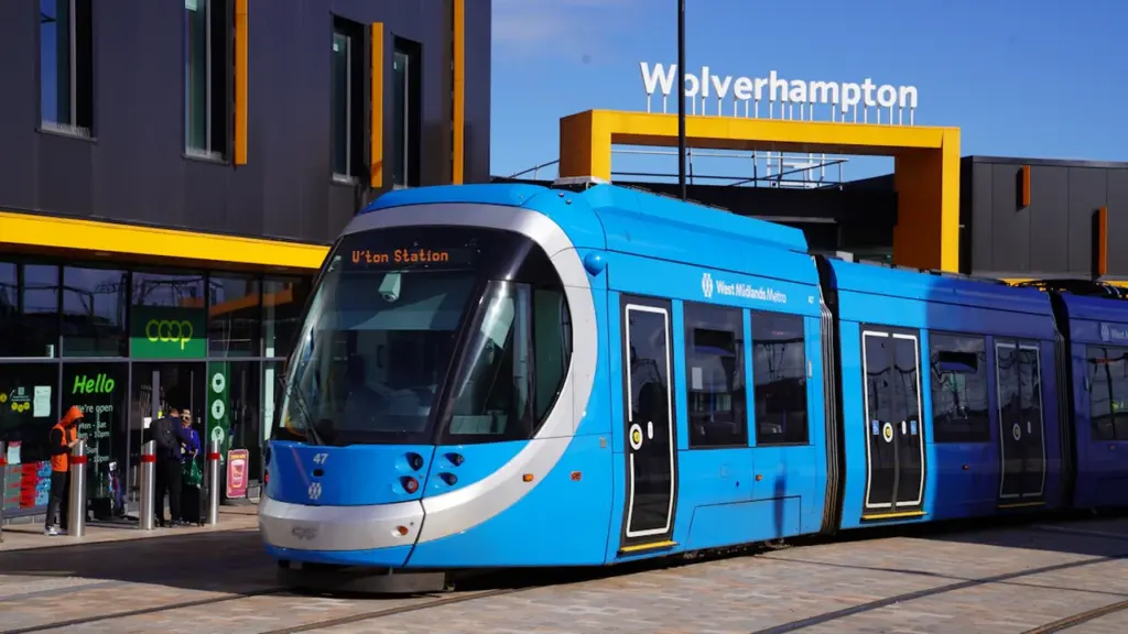 Modern West Midlands Metro tram arriving at the Wolverhampton railway station transport hub.