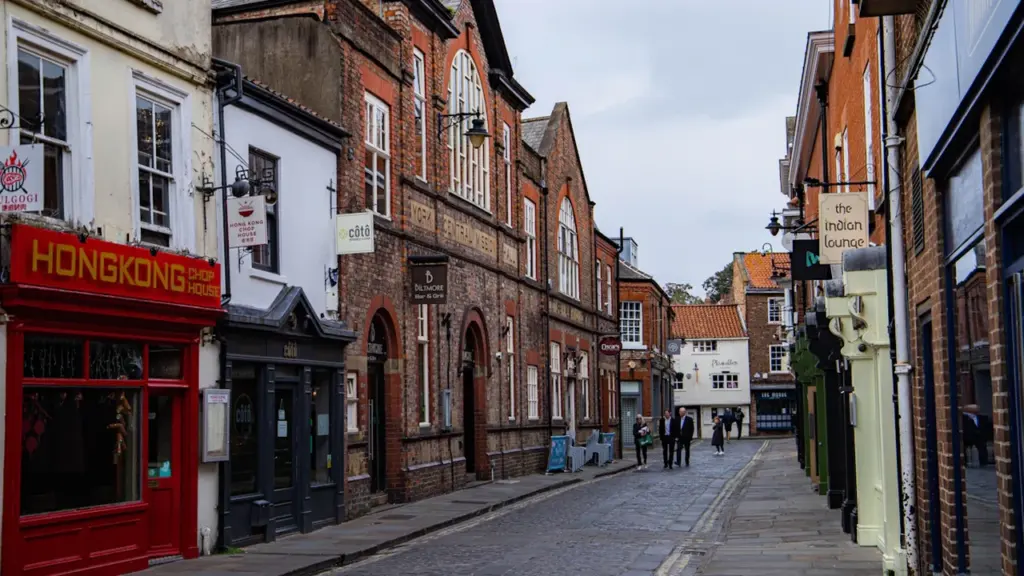 A narrow historic street in York with traditional brick buildings and local storefronts.