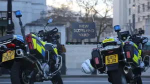Two UK police motorcycles parked in front of the New Scotland Yard headquarters building.