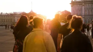 People walking across a sunlit city square during the late afternoon in England.