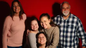 A diverse family posing together against a solid red studio background.