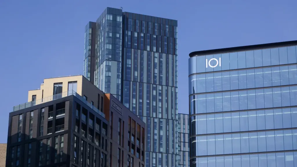 Modern office and residential skyscrapers against a clear blue sky in the UK.