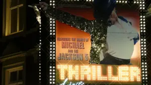 Bright illuminated billboard for a musical production in London at night.