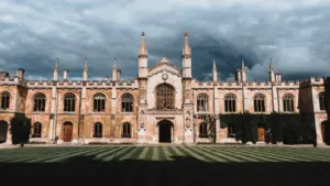 Architectural view of Corpus Christi College, Cambridge, featuring stone buildings under a cloudy sky.