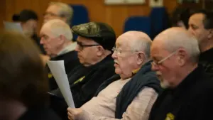 Group of older men in a meeting setting reviewing printed documents together.