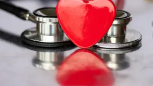 A stethoscope resting on a surface with a red heart symbol.